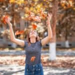 woman throwing yellow leaves