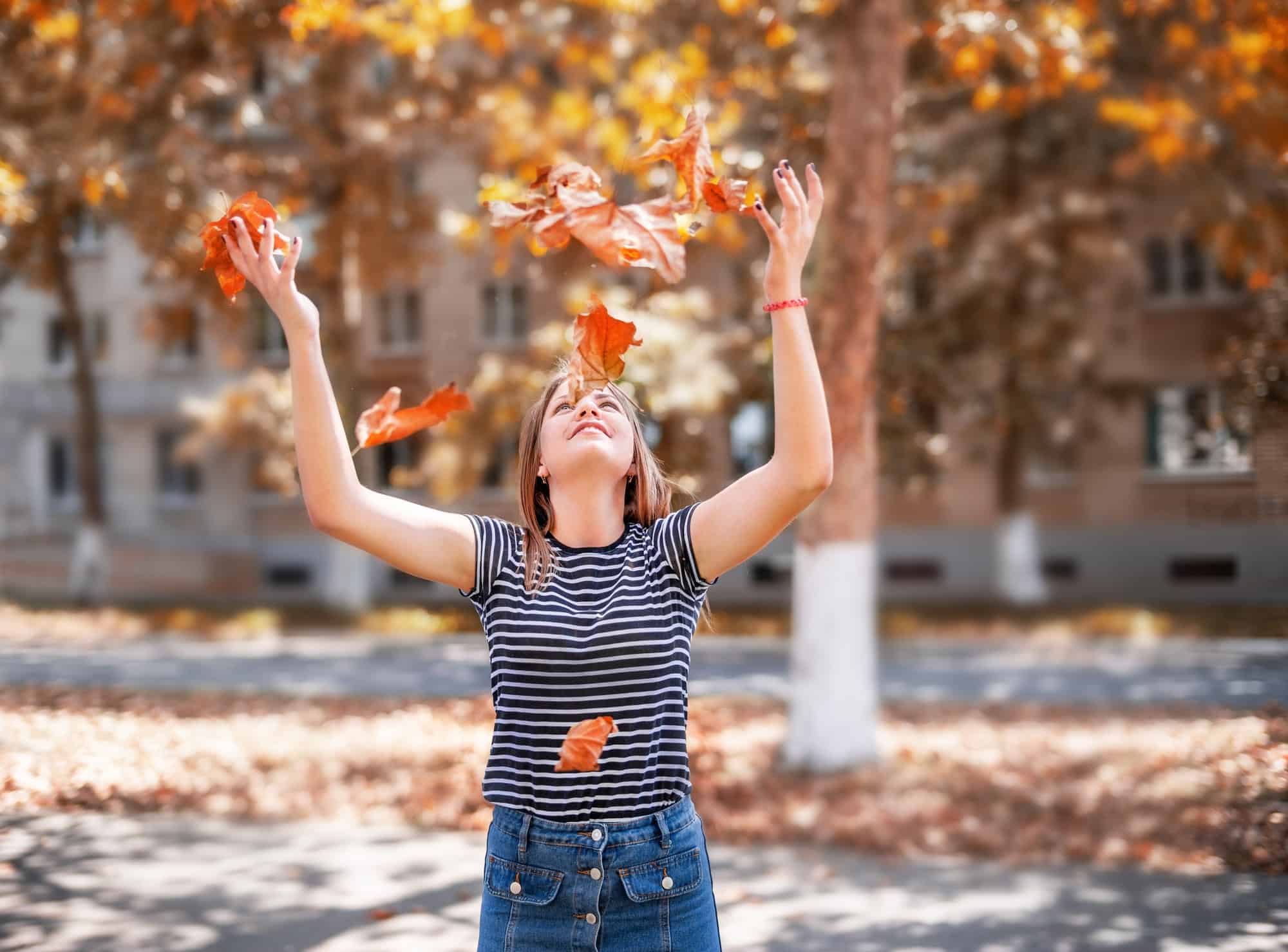 woman throwing yellow leaves